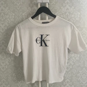 CALVIN KLEIN JEANS t-shirt - Ikonisk vit t-shirt 100% bomull med vintagekänsla från CK butik i Amsterdam. Löst uppvikta ärmar. Sömmen har släppt på insidan bak, enkelt att fixa, se bild.