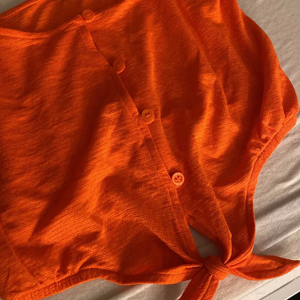 En super gullig liten topp i en Såå fin orange färg! Passar perfekt till sommaren när man fått lite färg på sig:) det är knappar som går att knäppa upp och man kan även knyta längst ner som man själv vill.  Storlek XS från H&M. Toppar.