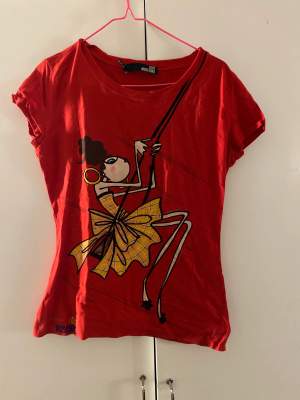 Röd t-shirt med tryck på en tjej på en gunga :P Köpt second hand men i väldigt bra skick och knappt använd av mig! 💕💕
