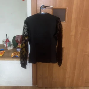 Svart blus - En svart långärmad blus med öppen rygg och ”puff armar”. Helt ny endast provad en gång.