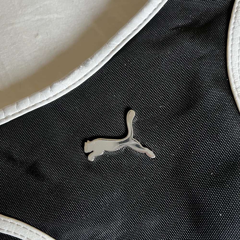En svart och vit handväska från Puma med silvrig logga, fint skick. Pris 100kr plus frakt 66kr 🖤. Väskor.