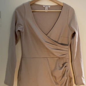 Beige klänning - Klänning från NELLY i storlek M, oanvänd. 