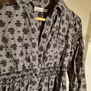 Blus - En grå blus med ett svart mönster på. Så skön och fin passform. Det är knappar pch en krage på den. Det är storlek S men är stretchig. 