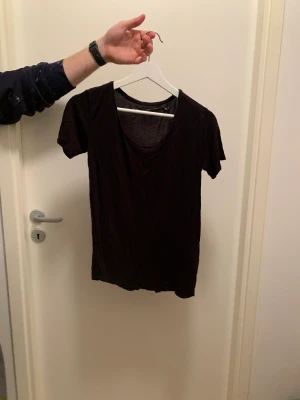 Svart T-shirt  - Svart tunnare T-shirt. Använt men fint skick. Lite sned i sömmarna. U-skärning fram. Finns två styxken
