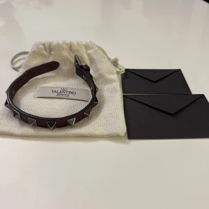 Valentino armband - Hej! Säljer nu mitt dina valentino armband då det ej kommer till användning och då jag köpt ett nytt. Armbandet är mörkrött med silvernitar, eftertraktad färg. Skicket är 8/10 då jag använt det ett dussintals gånger. Se bilder för skicket.Onesize fits all