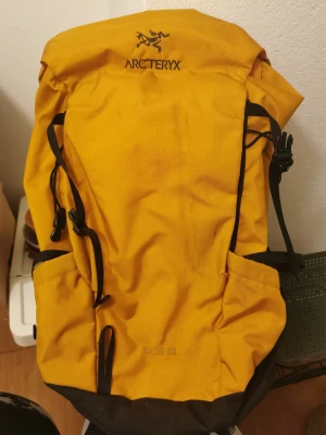 Arc'teryx Brize 32L Ryggsäck.  - Arc'teryx Brize 32L Backpack. Orange. För vuxna.  Ryggsäcken har åkt flygplan igenom länder till Malaysia och tillbaka, tyget är inte längre i nyskick men inget större fel på den. 