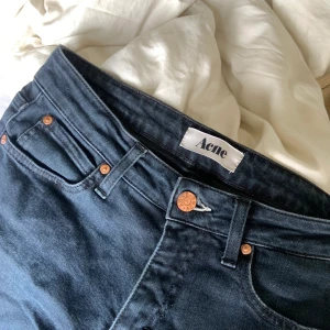 Acnejeans - Mörkblå (nästan svarta) tighta jeans från Acne med fransiga byxändar. 