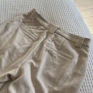 Beige Kostymbyxor - Ett par knappt använda beiga kostymbyxor i en kall ton! 💘 Dessa är straight leg / vida i benen. Materialet har ett fint mönster och de är i ett tjockt, kvalitativt tyg. Väldigt fina!! Storlek 36, passar S-M 💘