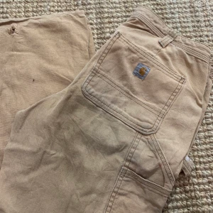 Carhartt Byxor - Ett par feta carhartt byxor. Gillar att dem är slitna på ett sätt som gör att man verkligen får en vintage känsla, bara att skriva för fler bilder :)  Ytterben 97,5cm Benöppning 23cm