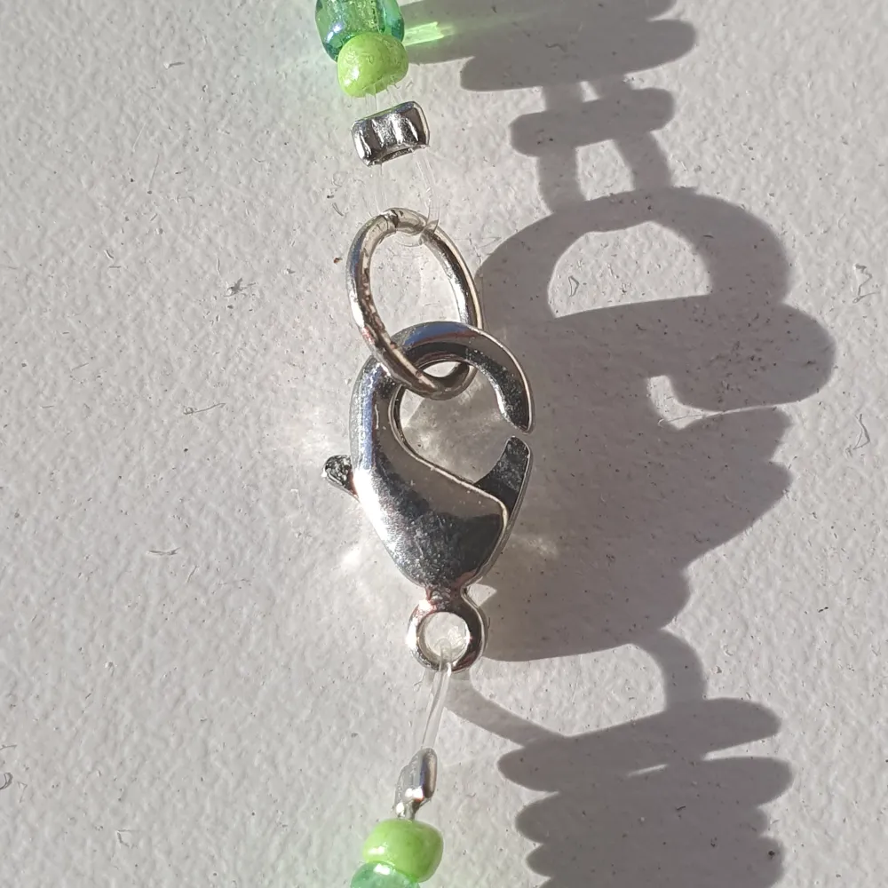 Halsband gjort med gröna glas och plast pärlor med klämma i metall.. Accessoarer.