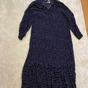 Prickig klänning  - En mörkblå lång klänning med vita och röda prickar. Den är från Hampton Republic i storlek L. Har endast användes ett få tal gånger. 