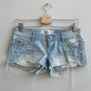 Lågmidjade jeansshorts Hollister  - Sjukt snygga och trendiga lågmidjade jeansshorts från Hollister i ljust denim och med snygga detaljer så som broderi och ”slitningar” 🤍🫶 Storlek W24, super fint skick. Bara höra av sig vid frågor eller då man vill ha fler bilder 🤍 köparen står för frakten 