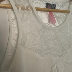 Vit klänning - Vit klänning med volang och spets från Lipsy London, väldigt bra skick. Storlek UK 10 (som en small)
