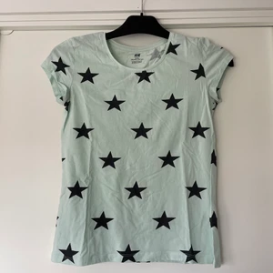 T-shirt - En blågrön t-shirt med svarta stjärnor på. Sitter åt lite grann men inte mycket:)          Fri frakt om du köper fler!