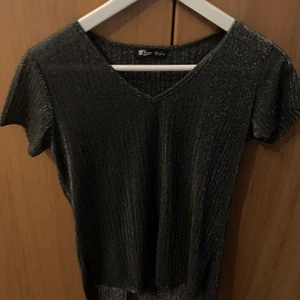Tröja  - En grå glittrande tröja, framsidan är kortare än baksidan 
