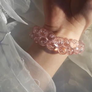 Plastpärlor - Söta, rosa plaspärlor på gummiband. Elastisk band. Kan användas som armband eller hårband. Bra skick, ej använd. 