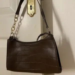 En liten brun handväska i fakeskin, aldrig använd 