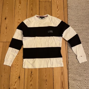 Tommy Hilfiger Crewneck - Tommy Hilfiger crewneck i färgen vit och mörkblå. Randig. Storlek small. Säljer denna snygga tröja eftersom att den inte passar mig längre. Finns inga speciella defekter på tröjan och skulle säga att skicket är 8/10. 