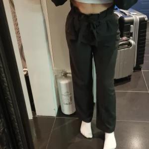 Högmidjade kosymbyxor - Högmidjade kostymbyxor från Bikbok i strl S. Snörning/skärp runt midjan som syns på bild. Väl använda då de varit mina favoritbyxor men fortfarande i bra skick. Kommer tyvärr inte till användning längre för mig🤗 Köparen står för frakt. 