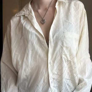 Satin skjorta  - Pierre cardin skjorta, i vad jag tror är satin med det finns ingen lapp. Loggan blir ett fint mönster utan att bli skrikigt!  Fin både oversized eller mindre som tänkt! 
