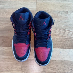 Air Jordans 1 Mid ”Banned” - Skorna är i strl 44 och skicket på skorna är 7/10 jag har använt skorna flera gånger men har tagit hand om dem så dem endå ser hyfsade bra ut. Jag köpte skorna för cirka ett och ett halvt år sen