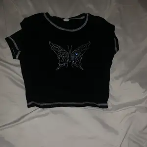 En svart T-shirt med en fjäril på, kontakta mig om ni är intresserade 