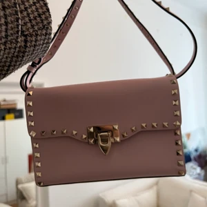 Valentino väska  - ”Valentino Garavani rockstud” väska i helt nytt skick. Köptes på Valentino i NK, Stockholm 2021 💓  Jag har nyligen flyttat och väskan har legat i sin påse sedan dess så den är använd max 5 gånger totalt sedan jag köpte den.   Denna färg går inte att få tag på längre och nypris på dessa är 13.195 kronor men jag kan självklart sälja för billigare vid snabb affär. Kan skicka egna bilder också vid intresse! Inga skador och ser ut som ny.   Påse, kvitton och allt som jag fick vid köpet finns kvar ☺️