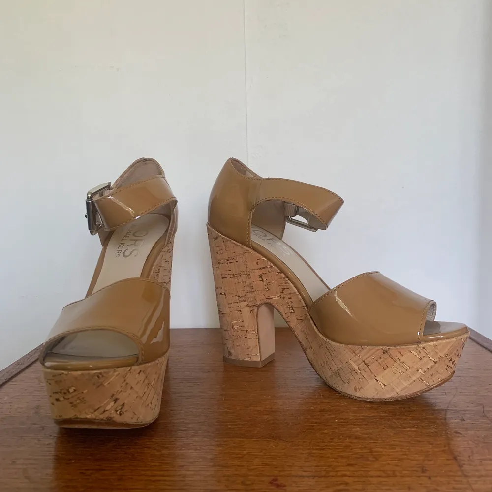 Beige patent leather platform sandals with cork heels. Brand: Kors Michael Kors. Size 38. Used but in very good condition.. Skor.