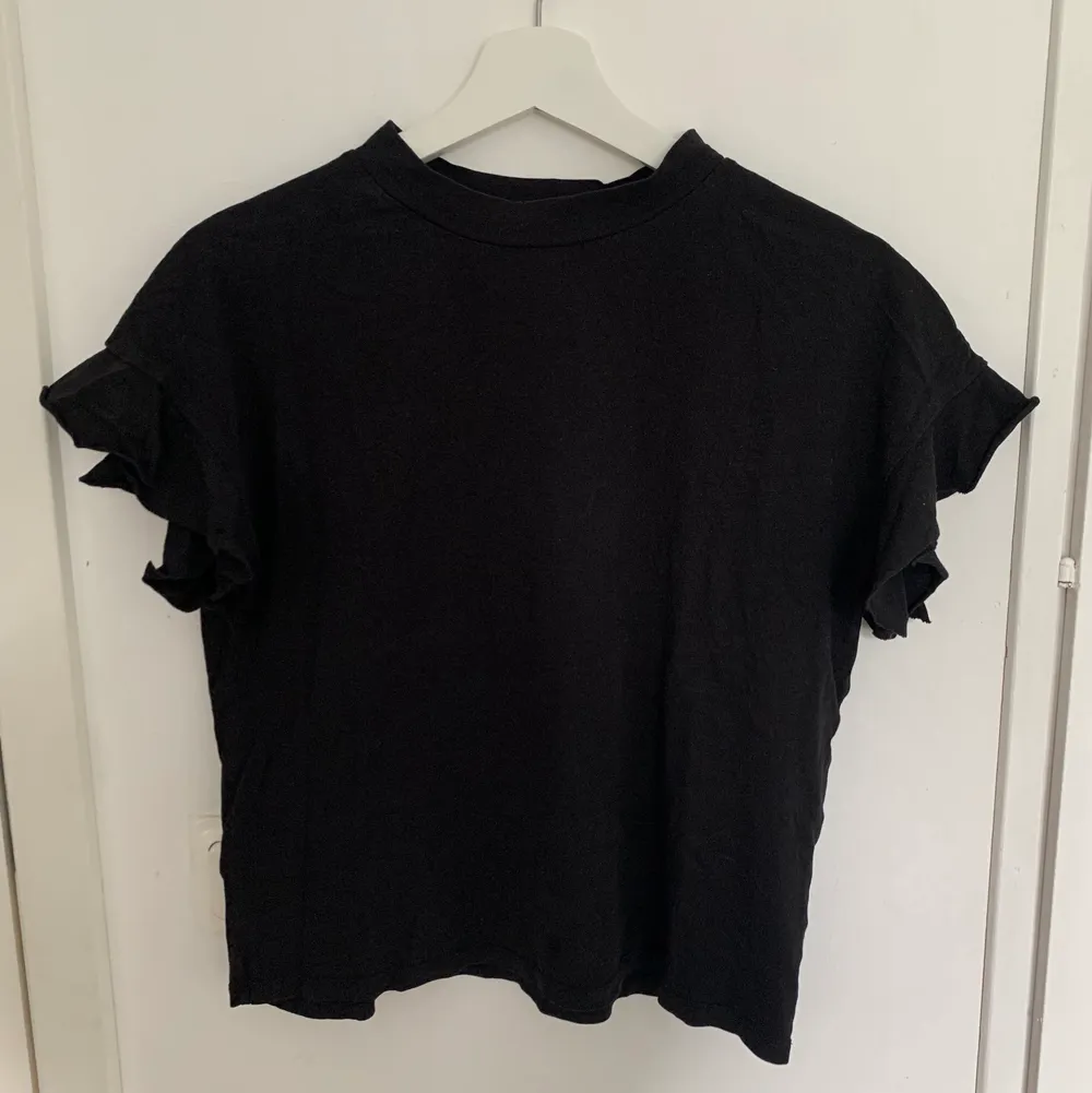 Svart t-shirt med volang ärm från lager 157, i storlek XS-S. T-shirten är i ett okej skick.. T-shirts.