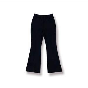 Utsvängda svarta byxor med slits vid byxänden med två fram fickor. ”Kostymbyxor” 98% Polyester 2% Elestan  Beninnerlängd: 77 Cm Benytterlängd: 100 Cm
