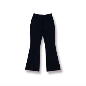 Flared pants  - Utsvängda svarta byxor med slits vid byxänden med två fram fickor. ”Kostymbyxor” 98% Polyester 2% Elestan  Beninnerlängd: 77 Cm Benytterlängd: 100 Cm