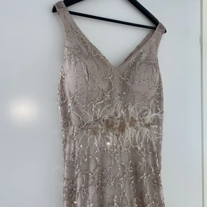 Balklänning / fest klänning - En fin balklänning helt ny i en beige färg. Klänningen har inbyggda kupor samt en underdel/ställ som får klänningen att falla fint på kroppen. 