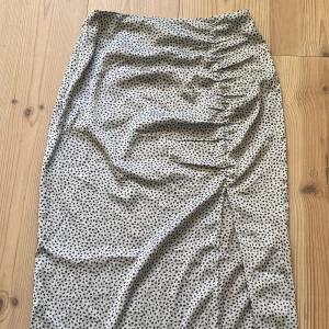 Långkjol med blommor - Säljer en jättefin högmidjad kjol ifrån H&m med små söta blomdetaljer! I mycket bra skick.