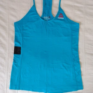 Oanvänt Reebok Activchill, blått/turkost linne - Turkost träningslinne från Reebok. Reebok Activchill Speedwick. Oanvänt men tvättat. Storlek S. Tvättrådslappar bortklippta. 