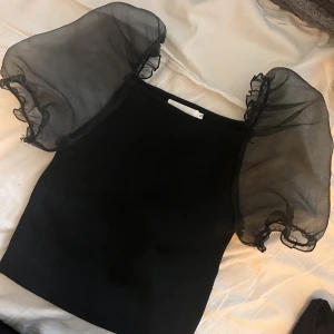 Svart festtopp - Svart topp med genomskinliga puffärmar. Storlek s från Boohoo. Använd någon enstaka gång. Mjukt material. 