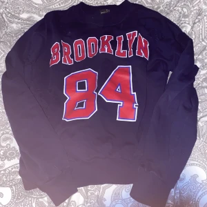 Blå sweater med slitningar  - Blå sweatshirt med slitningar och rött tryck. Storlek Xs men lite oversized så som en S, och använd ett par gånger. Superfin och skön. 65kr+frakt