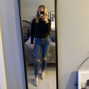 Mörkblå jeans med slitningar  - Säljer mina rätt så lågmidjade jeans med hål på knäna då de inte kommer till användning. De är i bra skick och är sällan använda.