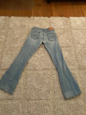 Ljusblå  low waist bootcut jeans från Levi's - Säljer ett par ljusblå Levi's jeans med bootcut passform. Klassisk femficksmodell med Levi's ikoniska sömmar på bakfickorna och läderpatch i midjan. 