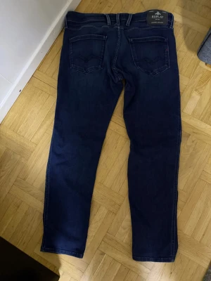Mörkblå jeans från Replay - Snygga mörkblå jeans från Replay med klassisk femficksdesign och raka ben. Jeansen har diskreta sömmar och en stilren look som passar till det mesta. Tillverkade i mjukt denimtyg för skön känsla och bra passform.