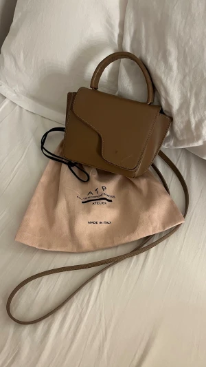 atp atelier väska - En jättefin brun väska från atp atelier, den är välanvänd och har därför lite skavanker här och där, men den går fortfarande att använda som vanligt!☺️ 