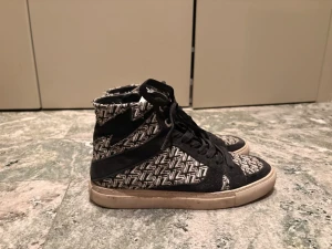 Zadig Voltaire skor  - Snygga high top sneakers i svart tyg med vitt grafiskt mönster över hela skon. Skorna har svarta skosnören och vit sula. Perfekta för dig som vill sticka ut med en unik design. Märket är inte synligt på bilderna.