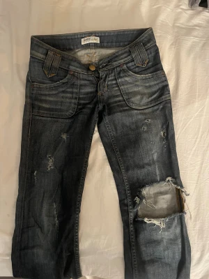 Lågmidjade bootcut jeans - Super snygga vintage jeans, köpte de på vinter och sedan gjort hålen själv! Mina favorit jeans men passar tyvärr inte längre så måste sälja. Fråga om mått!