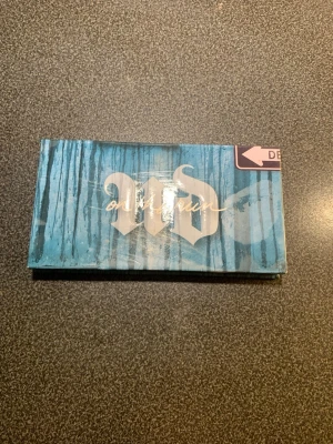 Urban Decay On The Run ögonskuggspalett - Säljer en Urban Decay On The Run ögonskuggspalett med åtta nyanser i både matta och skimrande toner. Färgerna sträcker sig från neutrala beige och bruna till metalliska blå och koppar. Paletten har en spegel i locket och ett snyggt blått fodral.