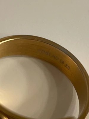 Guldfärgad ring med nitar från Edblad  - Cool guldfärgad ring från Edblad med flera rader av spetsiga nitar som ger en edgy vibe. Ringen är bred och har en blank finish som verkligen sticker ut. Perfekt för dig som vill ha något unikt och vågat i din smyckessamling.