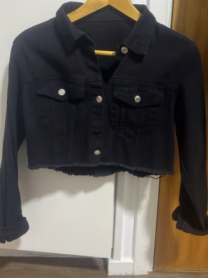 Svart croppad jeansjacka - Säljer en svart croppad jeansjacka med rå kant nertill passar perfekt nu när det börjar bli varmt ute 🤗använd en gång 