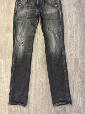 Replay anbass aged 05 - Säljer ett par svarta jeans med slitningar och tvättade detaljer. Jeansen har raka ben, klassisk femficksmodell och en cool, lite sliten look. Perfekta för dig som gillar en avslappnad och trendig stil. Kom med frågor och prisförslag 