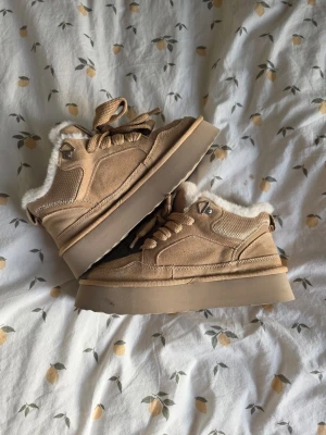 Varmfodrade Beige Kängor - XTI - 38 - Säljer ett par beige stövletter med chunky platåsula och snörning. Utsidan är i mockaimitation och insidan är fodrad med mjukt vitt foder för extra värme. Trendig modell för dig som gillar en mysig och modern look. Använda ca 3 gånger.