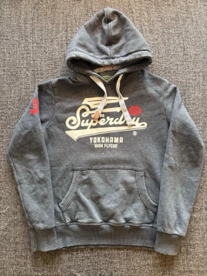 Superdry hoodie ~ sällsynt modell  - Säljer en eftertraktad hoodie från Superdry. Vintage 2000’s-modell | färg grå | storlek M | skick 9/10. Klassisk äldre Superdry-design som är svårare att hitta idag. Kan även gå ner lite i pris vid snabb affär. Färg ~ Grå/blå