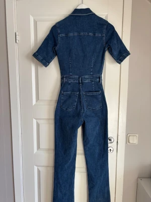 Blå denim jumpsuit med dragkedja - Snygg blå denim jumpsuit med korta ärmar och boot cut Ben (svårt att visa) super bekväm och  figurnära!🤩 knapt använd 