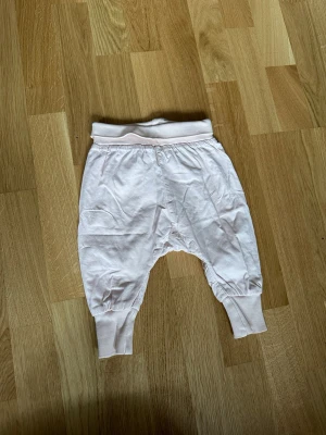 Ljusrosa mjukisbyxor med muddar - Säljer ett par ljusrosa mjukisbyxor med breda muddar i midja och benslut. Byxorna har en avslappnad passform och är gjorda i mjukt bomullstyg. Perfekta för chill dagar eller när du vill ha det extra bekvämt.